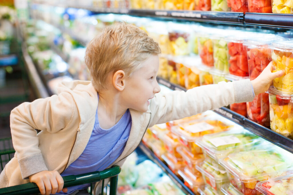 Little boy in grocery store reaching for container of fruit.
Picture by Aleksei Potov.